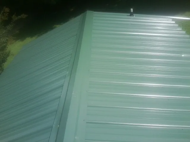 New green metal panels meeting at the ridge of a roof — Flat Roof Repair work by our crew in Dateland
