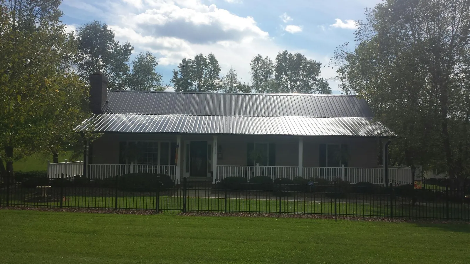 Gray metal roof on a brick ranch with a full width front porch — Gutter Guard Installation work by our crew in Dateland