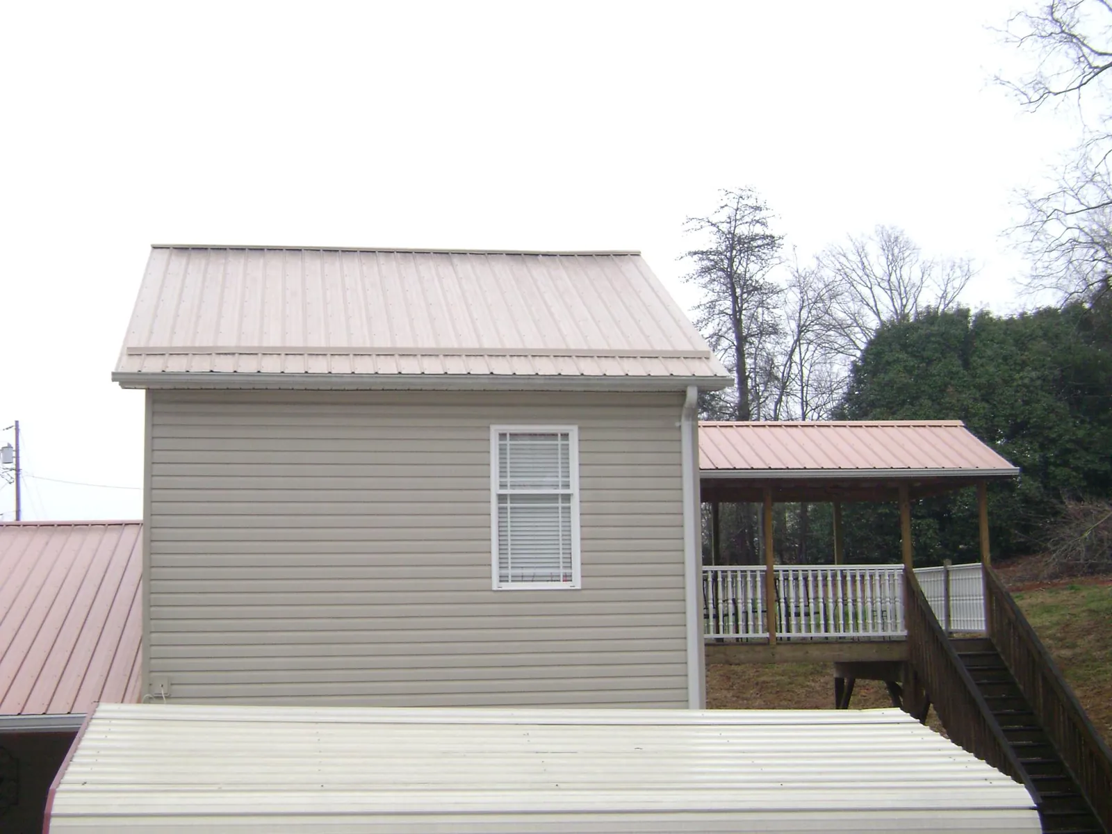 Tan metal roofs on a two story addition and attached porch, from a Roof Replacement job in Dateland