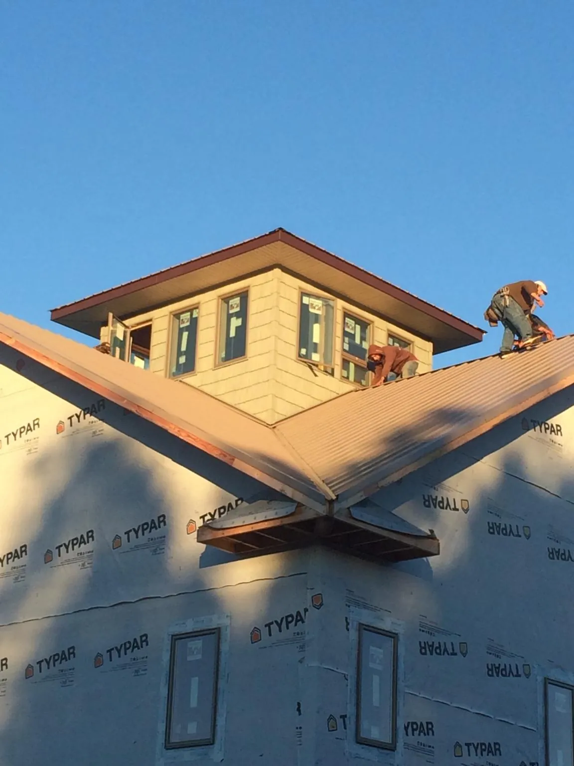 Roofers working around a rooftop cupola on a new metal roof at sunset — Roof Waterproofing in Dateland by Roofing Brothers